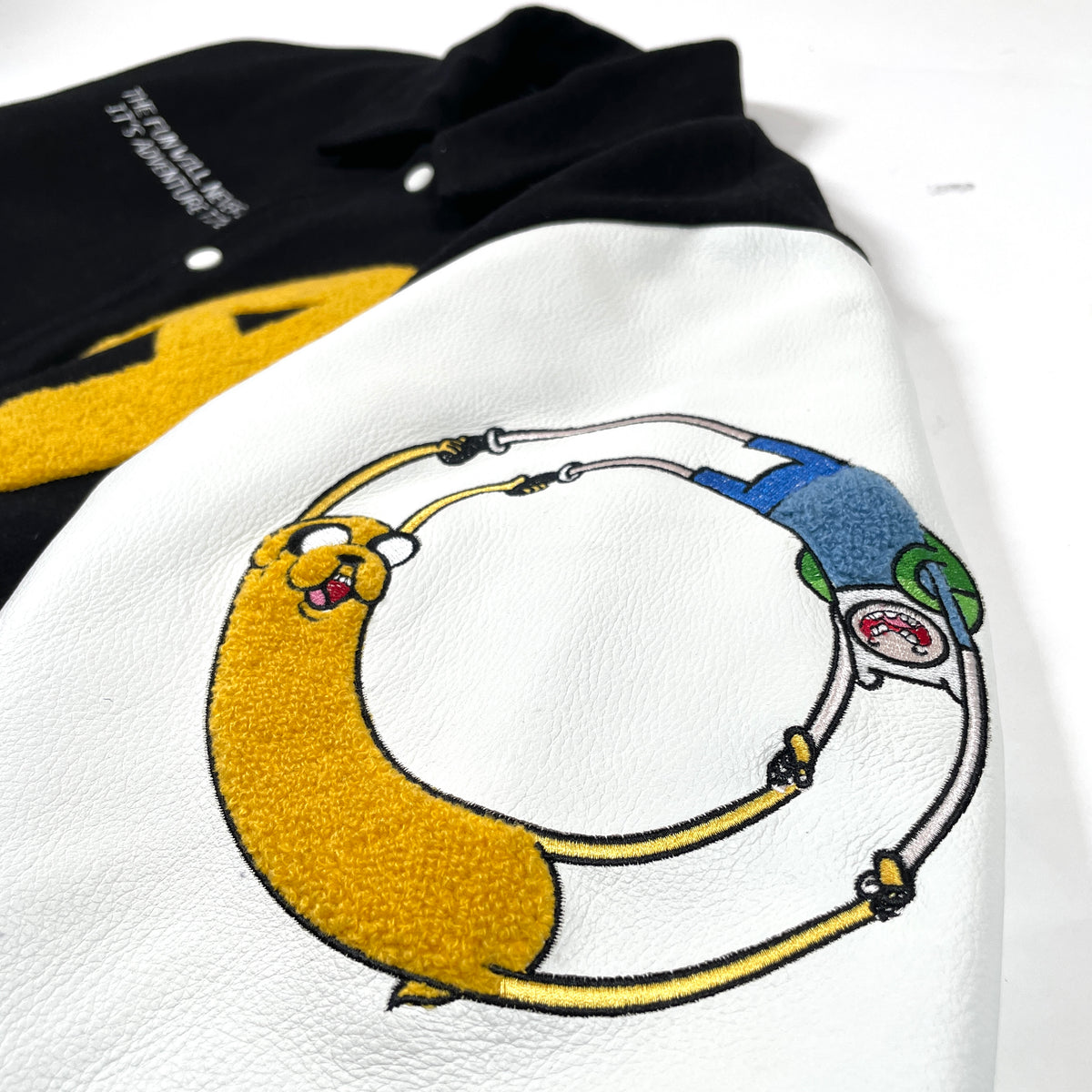 Close-up of Finn and Jake character embroidery on the genuine leather sleeve