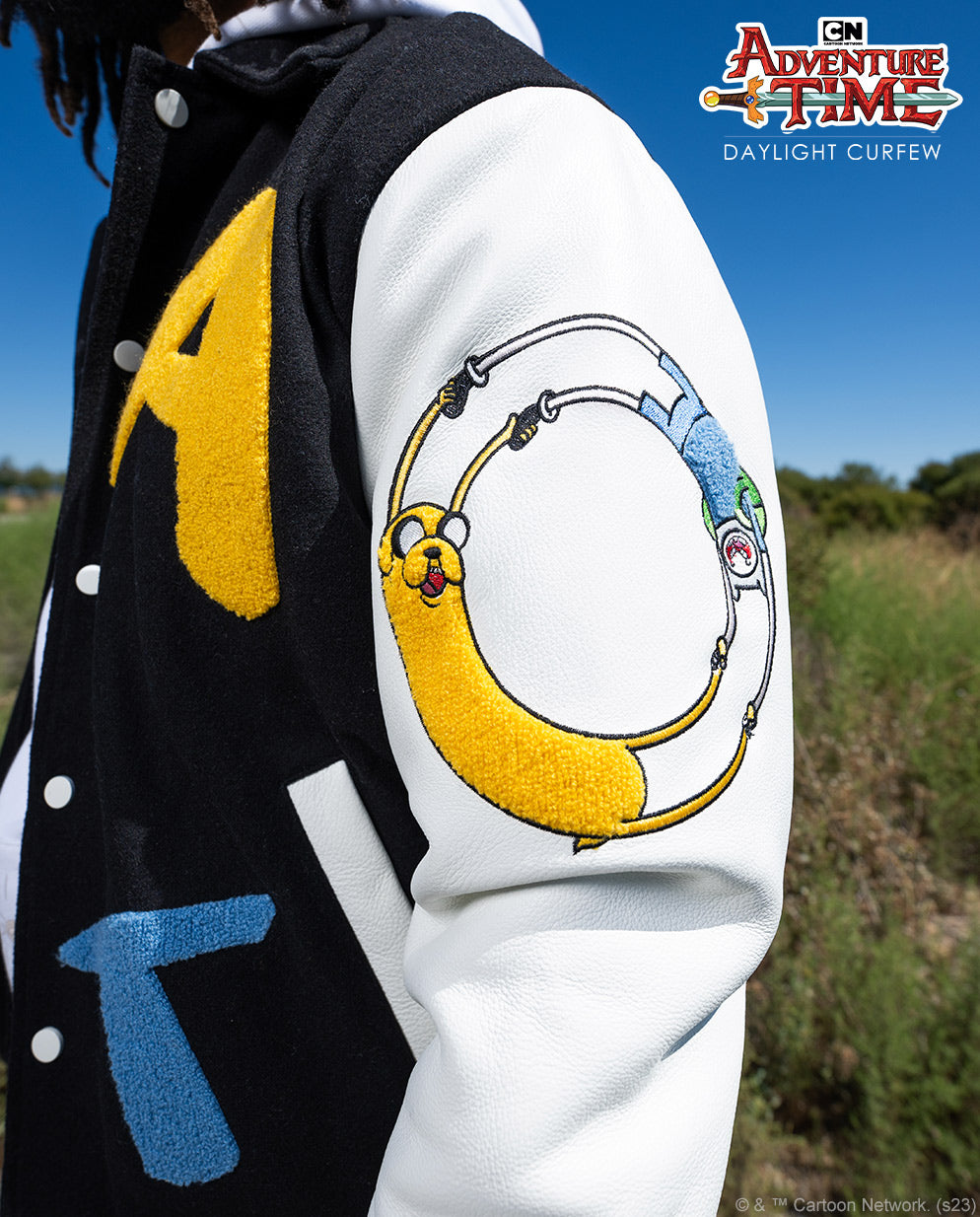 On-body detail of the yellow A and blue T chenille patches, black wool-blend body and cream sleeve