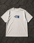 DLC Paint Tube Tee Ivory, overhead flatlay on asphalt